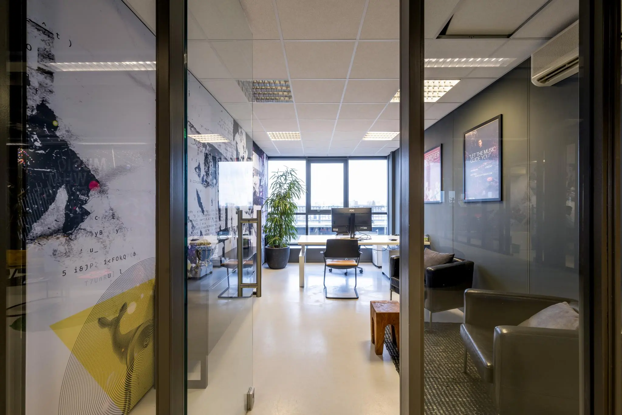 Modern kantoor aan de Anthony Fokkerweg met glazen wanden, bureau, zithoek en uitzicht op buiten.